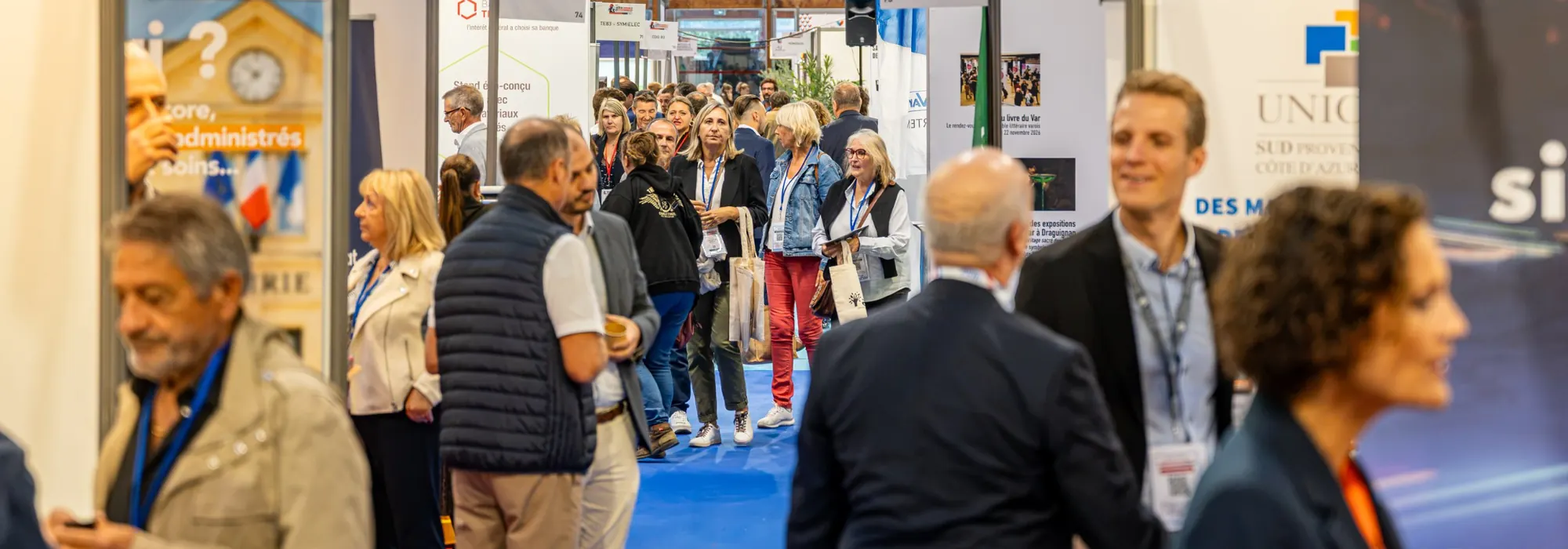 Visiteurs, élus et exposants se croisent dans une allée du salon, entre les stands