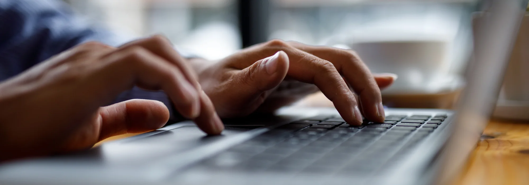 Mains qui écrivent un message sur le clavier d’un ordinateur portable pour contacter l’équipe du Salon des Maires des Pyrénées-Orientales